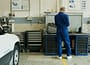 man in blue overall beside white car in service garage